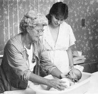 1988 Nurse instructing new mother in infant care.