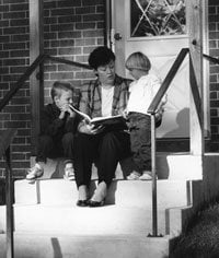 Woman on steps reading to children