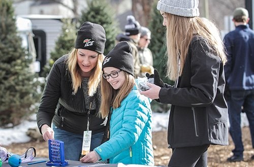 A family takes a break during action at Hockey Day Minnesota 2018 to enjoy the Project Brainsafe booth at the Winter Village.