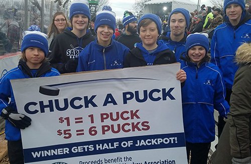 Volunteers from the Sartell Youth Hockey Association entertained fans at Hockey Day Minnesota 2018 with a Chuck a Puck contest with proceeds benefiting the Minnesota Sled Hockey Association.