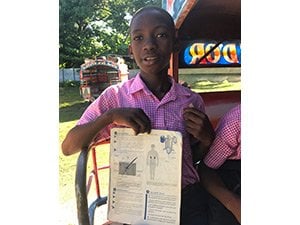 A Haitian boy shows his book about kidneys